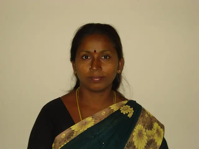 In the image there is a lady standing. Around her neck there are chains and also there is a nose...