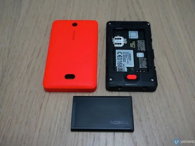 In this image I can see a black colour phone, an orange colour back case and here I can see a black...