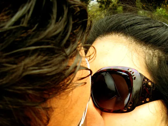 In this picture I can see two people who are kissing each other and they are wearing spectacles.
