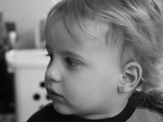 This is a black and white picture. In this picture a baby is highlighted and this baby is looking...