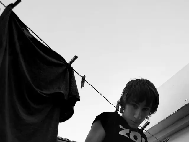 In this image there is a person hanged on a rope with clothes beside him, behind him there is a...