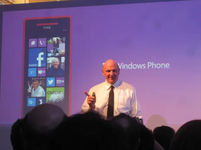 In the picture we can see a man standing and giving a seminar, he is with white shirt and black tie...