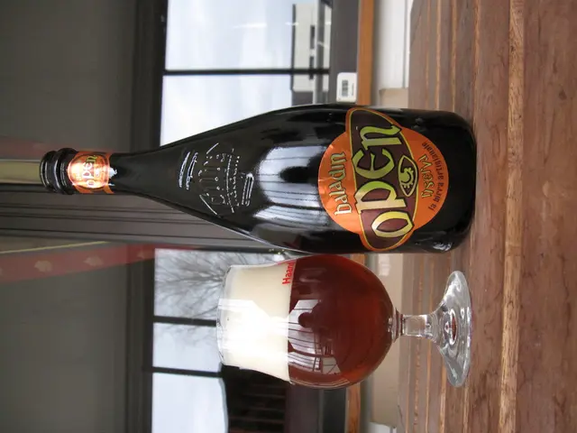 There is a bottle with label on it. Near to the bottle there is a glass with liquid. In the back...