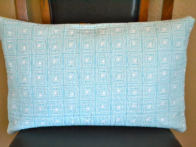 In this image we can see a chair. There is a pillow on the chair. There is a wall behind a chair.